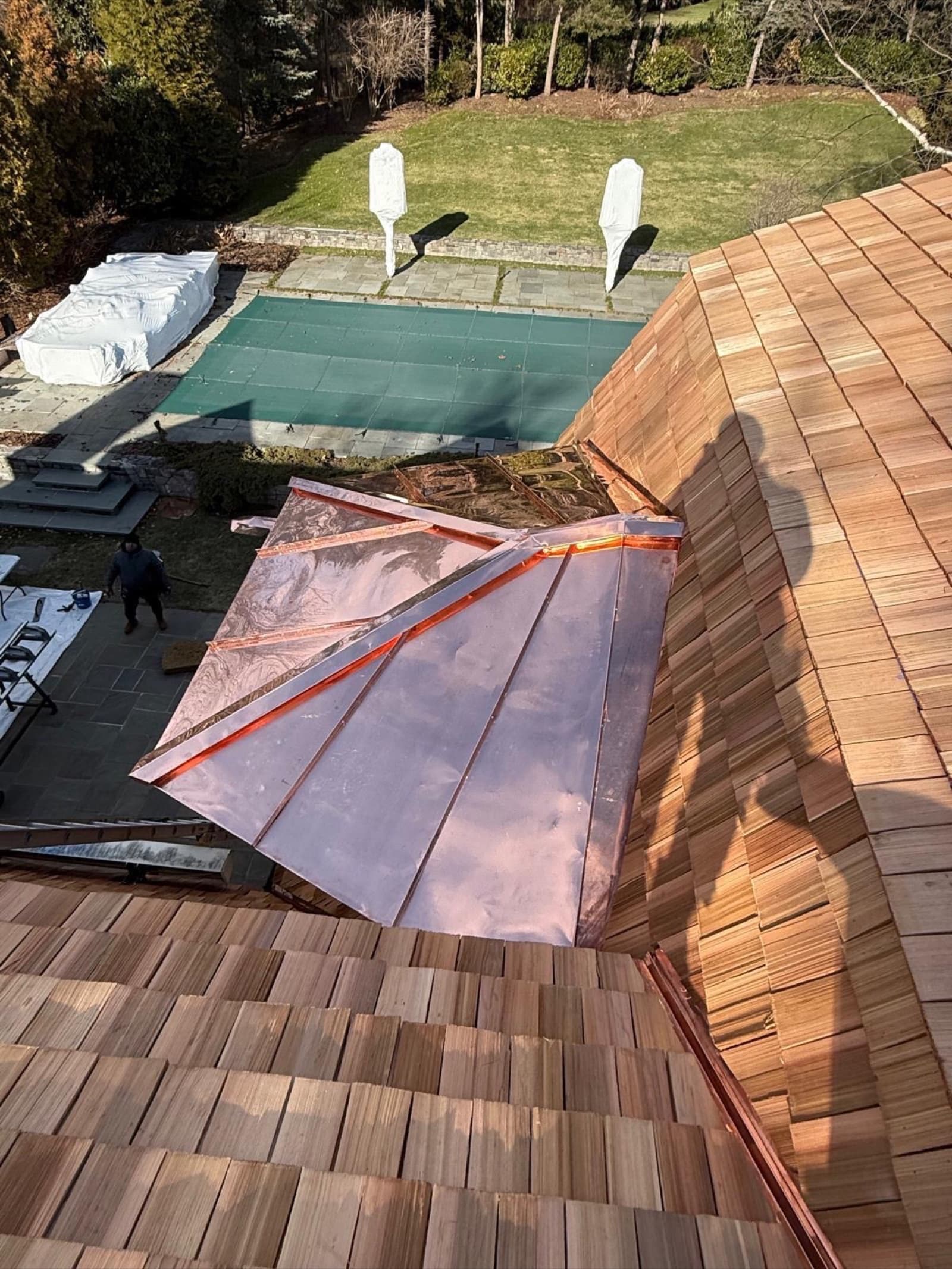 Copper standing-seam roof on a cedar-shake luxury home — premium metal installation by Zubar Roofing.