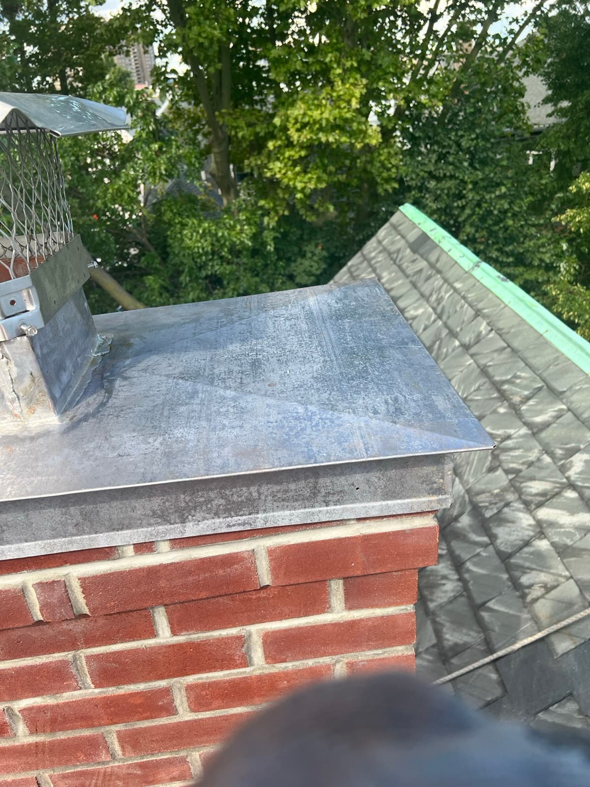 Galvanized chimney cap on a brick chimney over an asphalt roof by Zubar Roofing in New Jersey.
