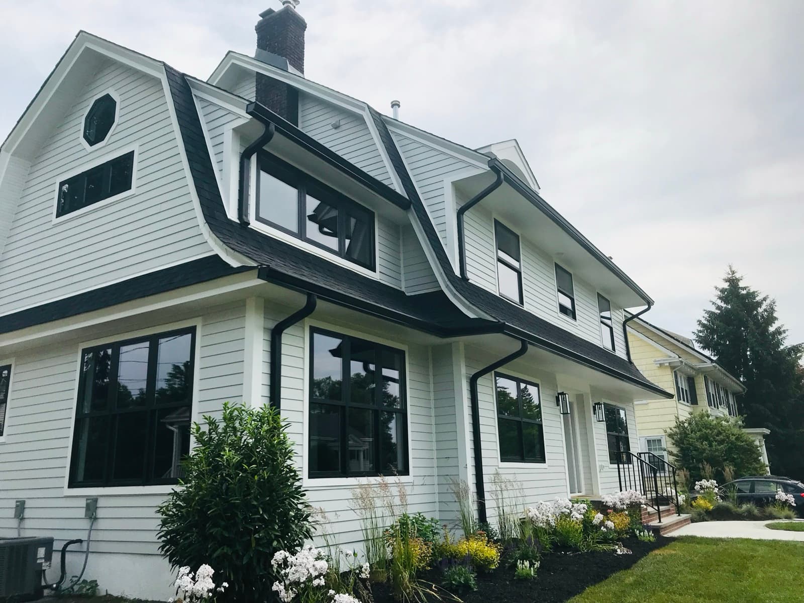 Completed gambrel roof with architectural shingles and seamless gutters on a New Jersey home.