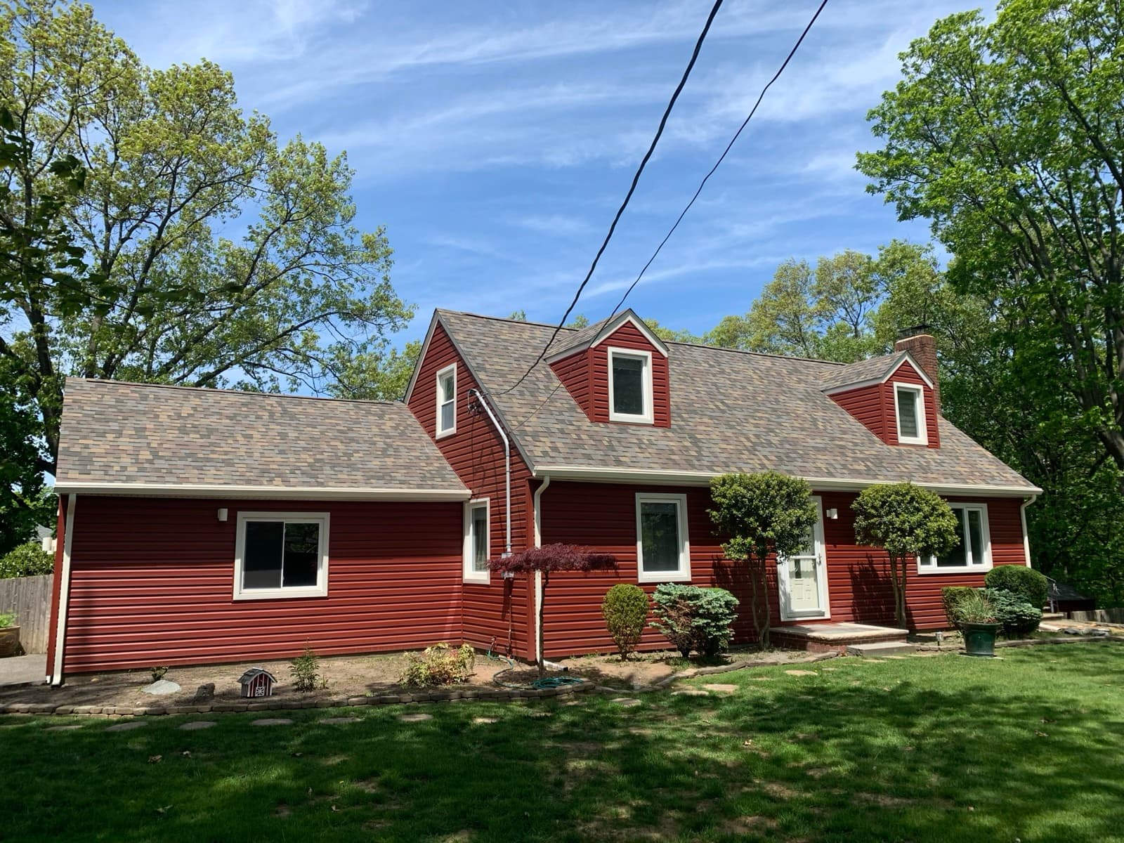Completed shingle roof on a red Cape Cod home in New Jersey by Zubar Roofing.