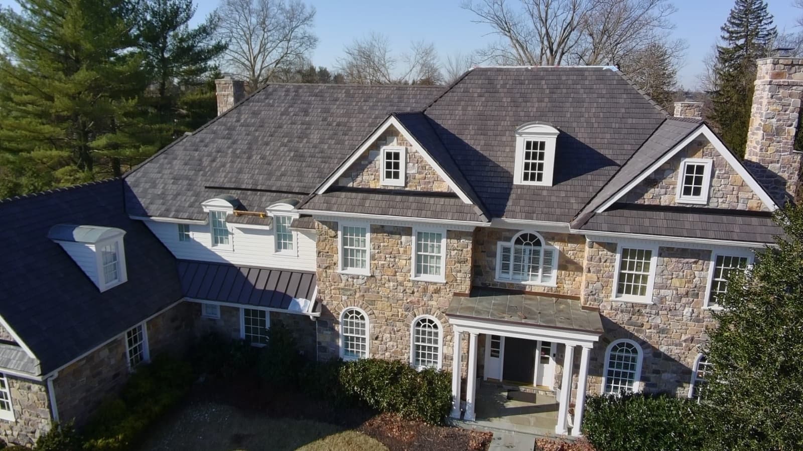 Aerial view of a designer roof on a New Jersey stone mansion installed by Zubar Roofing.