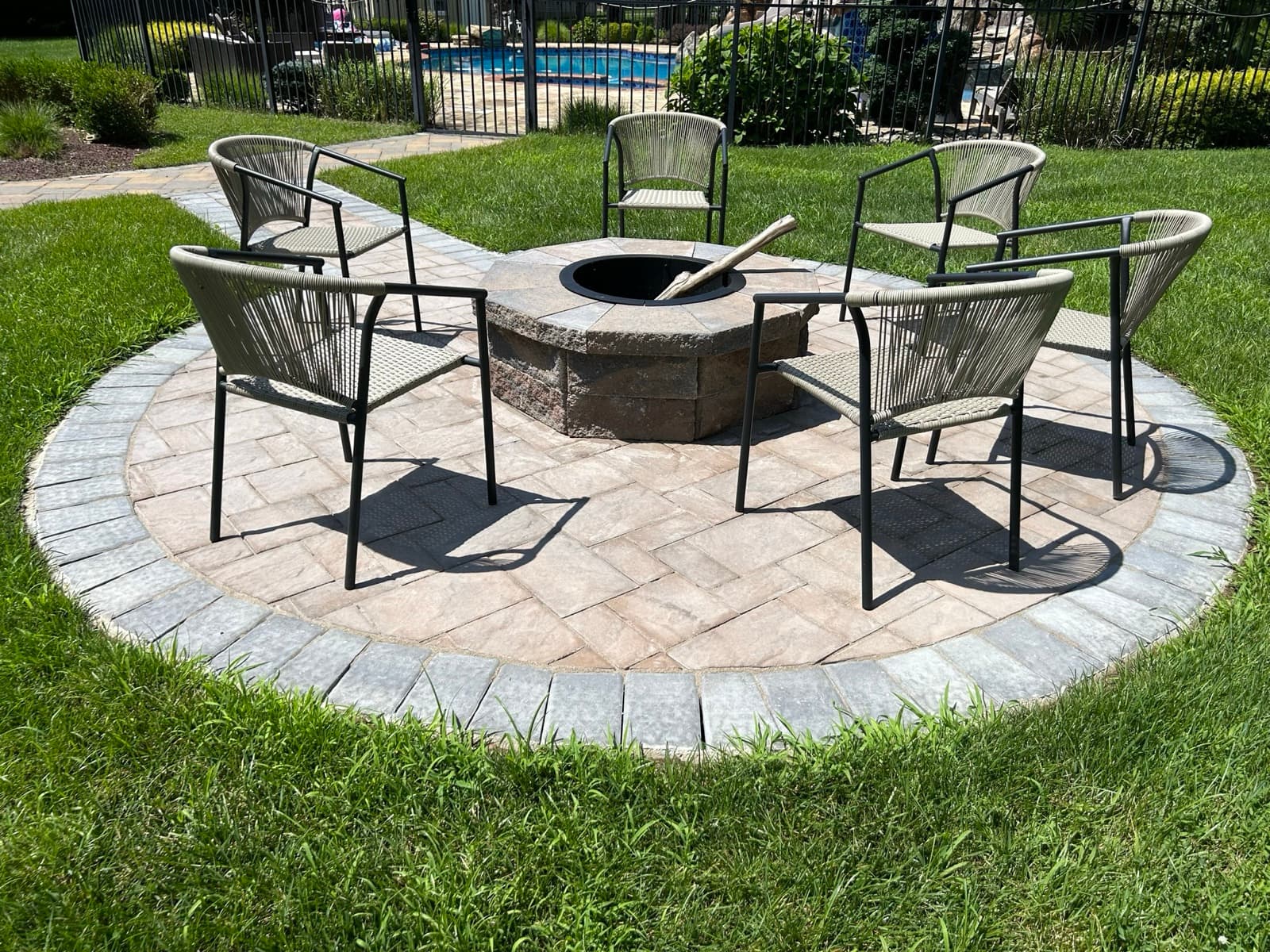 Paver patio with a fire pit in a poolside backyard — exterior work by Zubar Roofing in New Jersey.